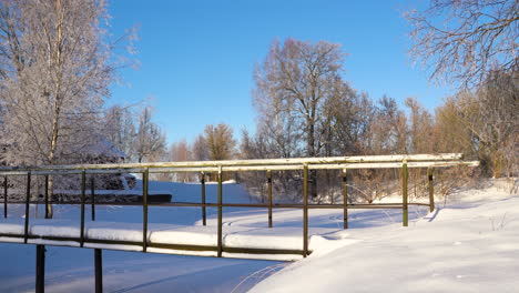 snow covered metal bridge on sunny winter morning in countryside, static shot