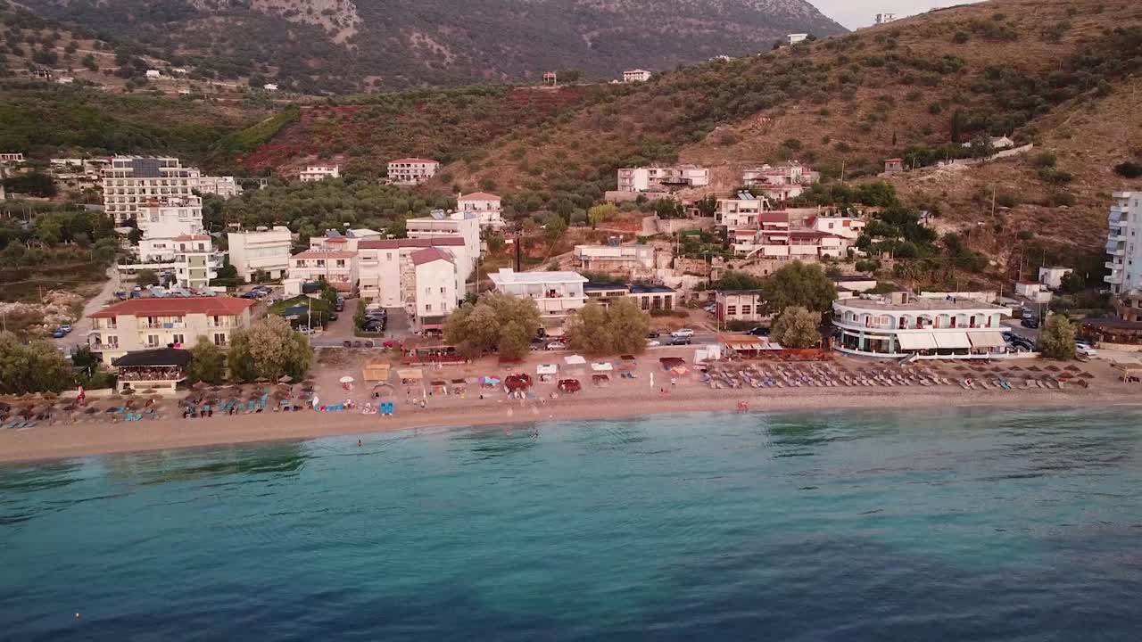 Aerial view of coastal village with turquoise beach at sunset in Albania