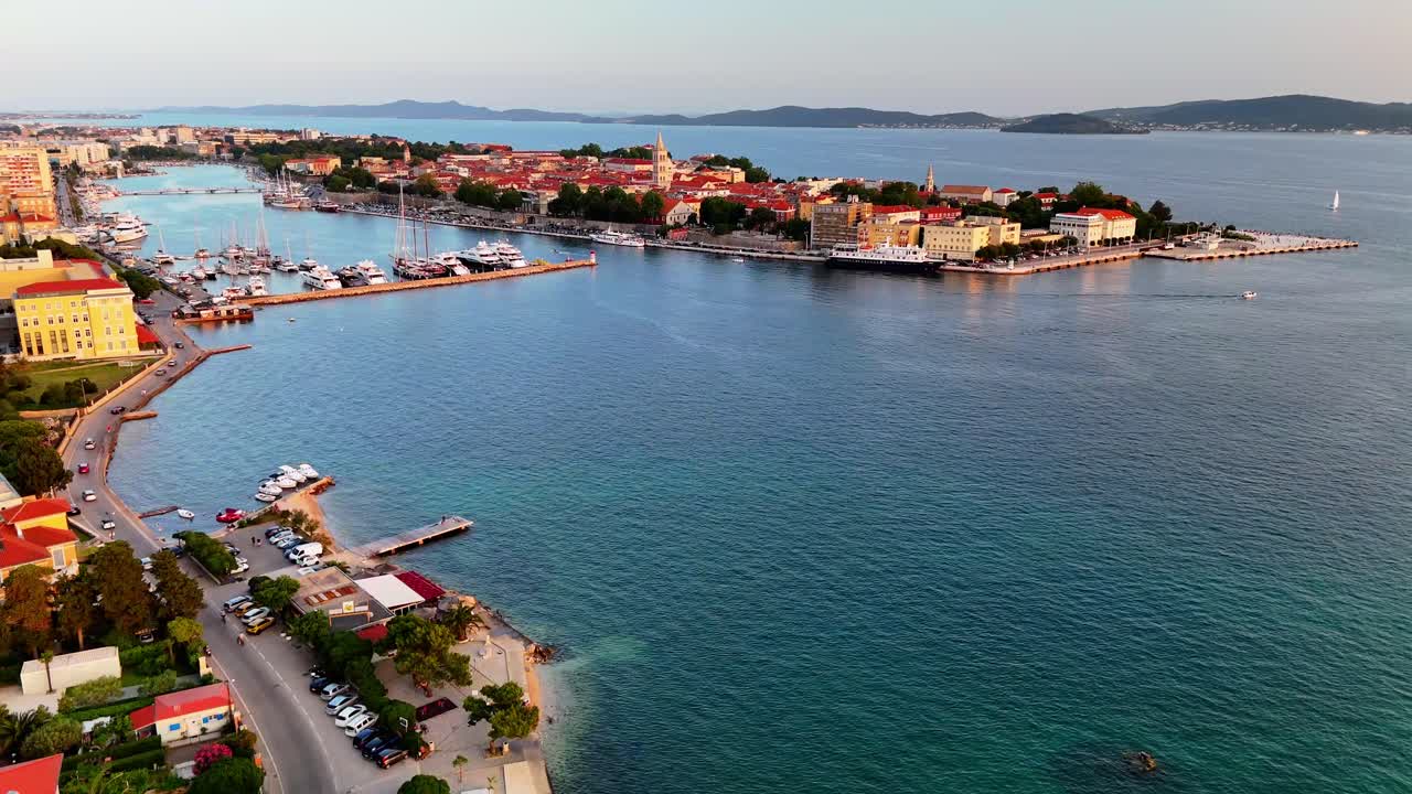 Aerial drone footage of Zadar, Croatia. Flying toward the old town at sunset, glowing Adriatic waters and historic skyline in stunning evening colors.