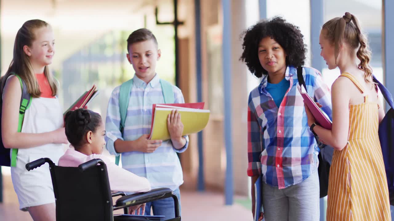 Happy diverse and disabled schoolchildren talking together in school