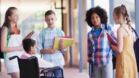 Happy-diverse-and-disabled-schoolchildren-talking-together-in-school