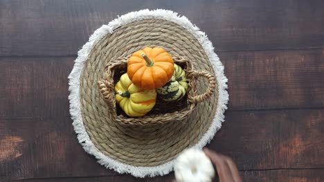 hand reaching into a basket of pumpkins