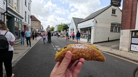 hand holding cannoli on busy arundel street