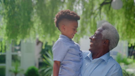 portrait of loving grandfather holding grandson in arms in garden at home