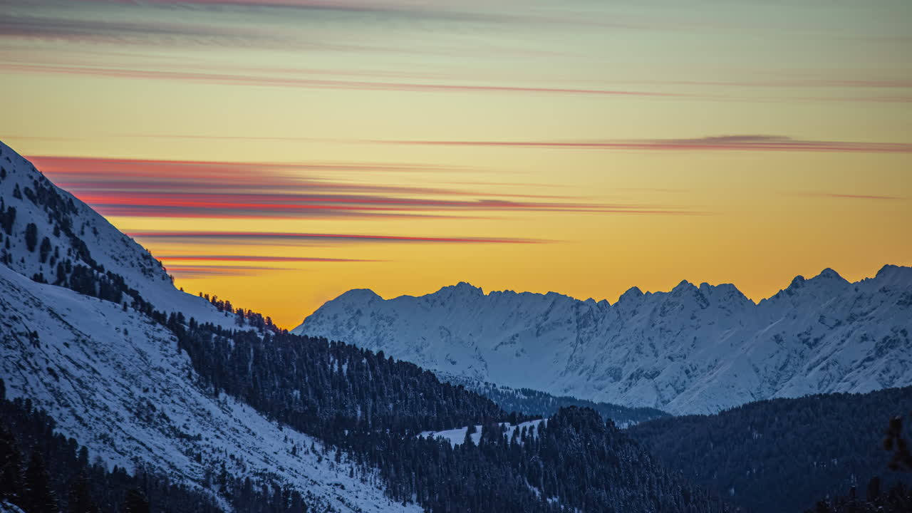 Tramonto giallo e calar della notte su un terreno montuoso aspro e invernale - time-lapse