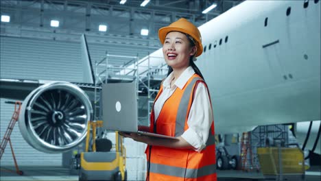 ingeniera de aviación femenina con una computadora portátil en el hangar