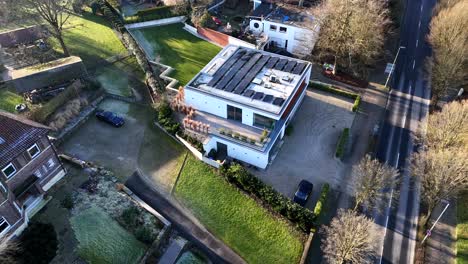 icy solar panels on roof of luxury villa in town of usa. aerial top down shot. sunny winter day in upper class neighborhood.