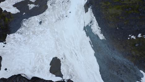 Peaceful-flight-over-glacier-reveals-a-river-flow-and-contrasting-green-vegetation-in-Fiordland,-New-Zealand,-South-Island