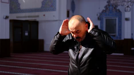 older man stands and prays in a mosque 2