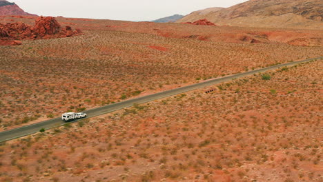 Toma-Aérea-De-Seguimiento-De-Un-Automóvil-Que-Arrastra-Un-Remolque-De-Casa-Rodante-A-Través-De-Los-Desiertos-De-EE.-UU.