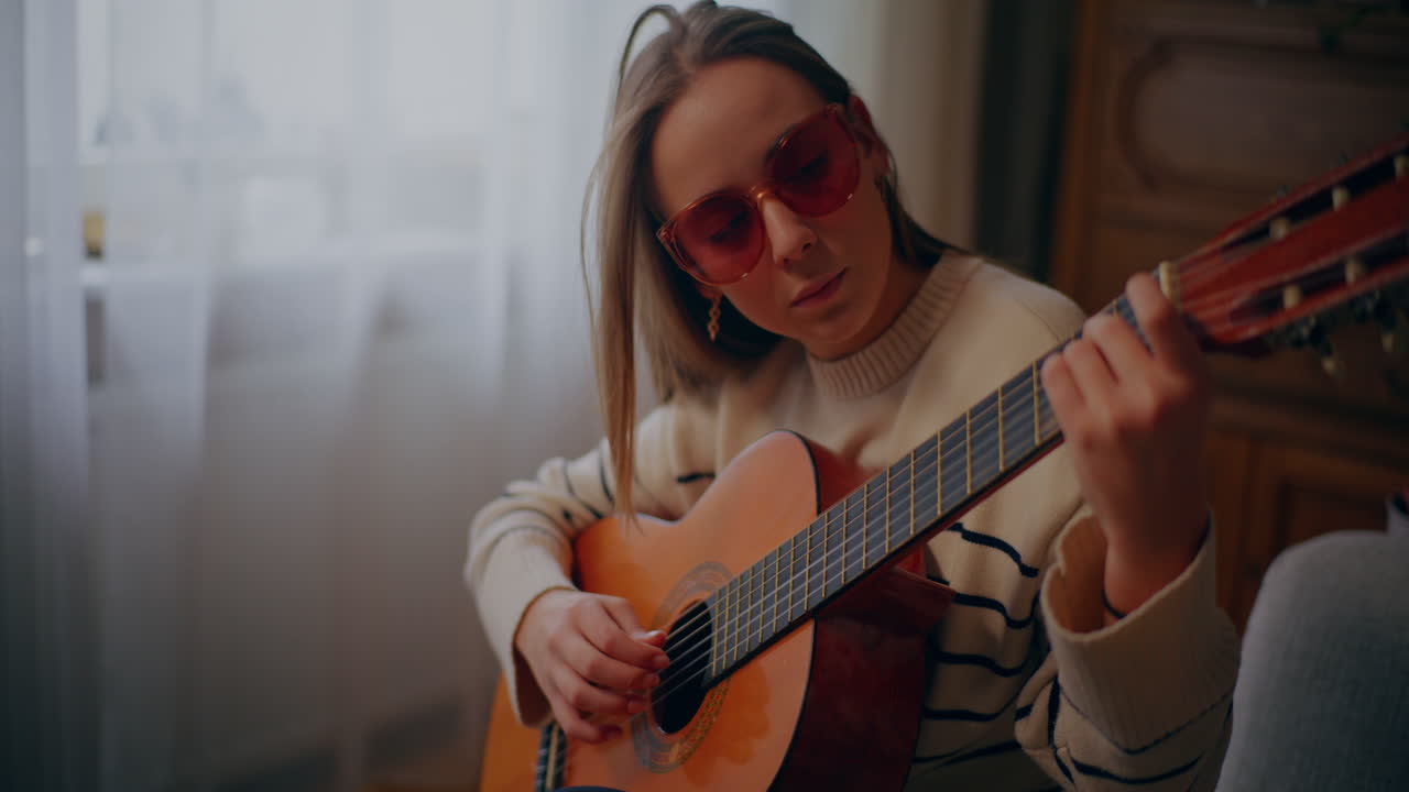 Kvinna spelar gitarr, skriver låt, komponerar musik
