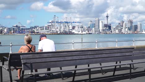 couple relaxing on a bench with auckland city skyline in the background
