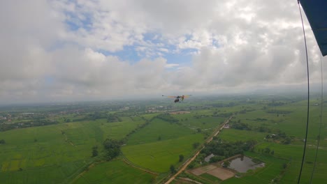 POV-Aus-Dem-Cockpit-Eines-Ultraleichtflugzeugs-Mit-Einem-Anderen-Regenbogenflügelflugzeug,-Das-Davor-Fliegt