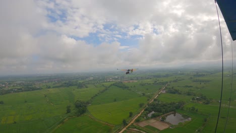pov desde la cabina de un avión ultra ligero con otro avión de ala arco iris volando en frente