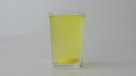 glass of water with an effervescent vitamin c tablet, white background