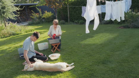 family washing clothes and playing with a dog in the garden