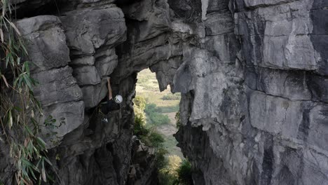 rock climber ascending treasure cave rock-face summit, yangshuo china, aerial view