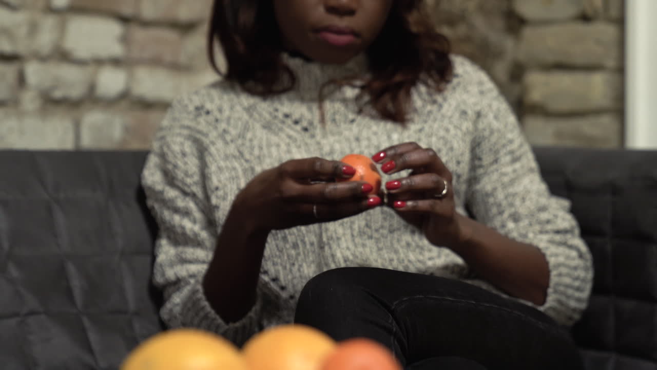 Pull focus to a woman with a mandarin, orange sitting on