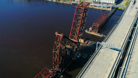 aerial view of a lift bridge opening for a tugboat and barge