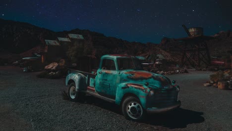 vieja camioneta vintage oxidada de estados unidos de pie en el desierto de nevada. coche retro en una ciudad fantasma estadounidense. cinemagraph ciclo de tiempo de video sin costuras de las estrellas que se mueven a lo largo del cielo.