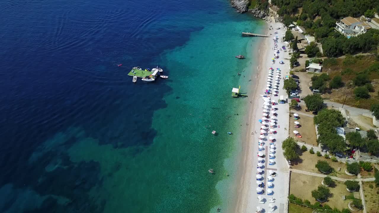 Aerial view of the coastline, beach, hotels and boats at the sea in Greece. Descending drone