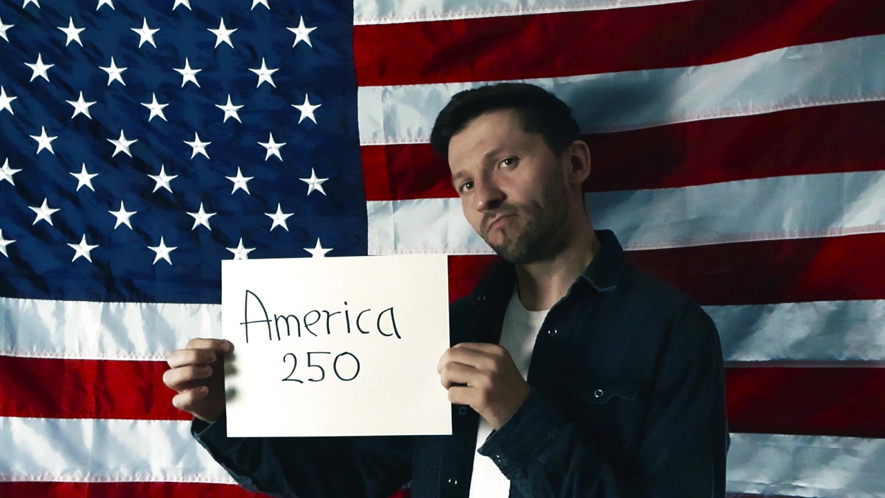Homem americano orgulhoso em frente a uma bandeira dos Estados Unidos, segurando uma placa que celebra o 250º aniversário da América