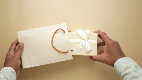 person holding a gift box and shopping bag