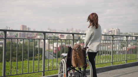 Mother-and-daughter-with-disability-look-at-city-panorama