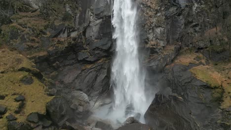 una poderosa corriente de agua cae desde la cima de una montaña sobre una superficie de roca negra creando salpicaduras