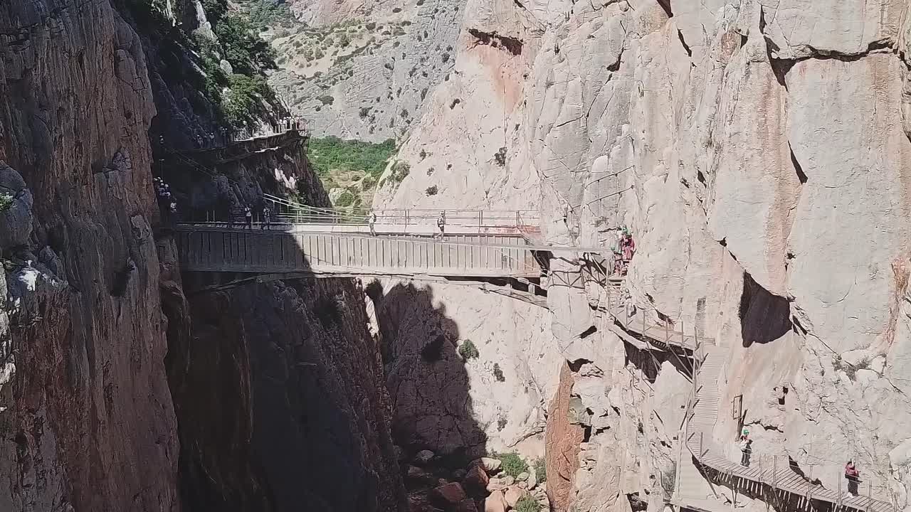 Besøkende krysser en trebro i en canyon i Malaga, Spania