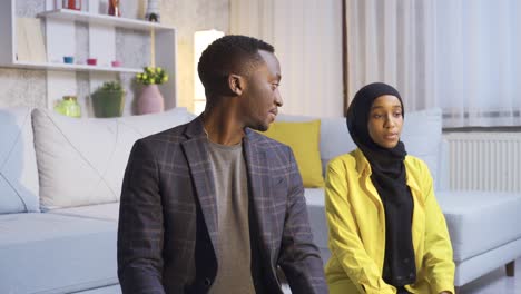 muslim african married couple praying at home.