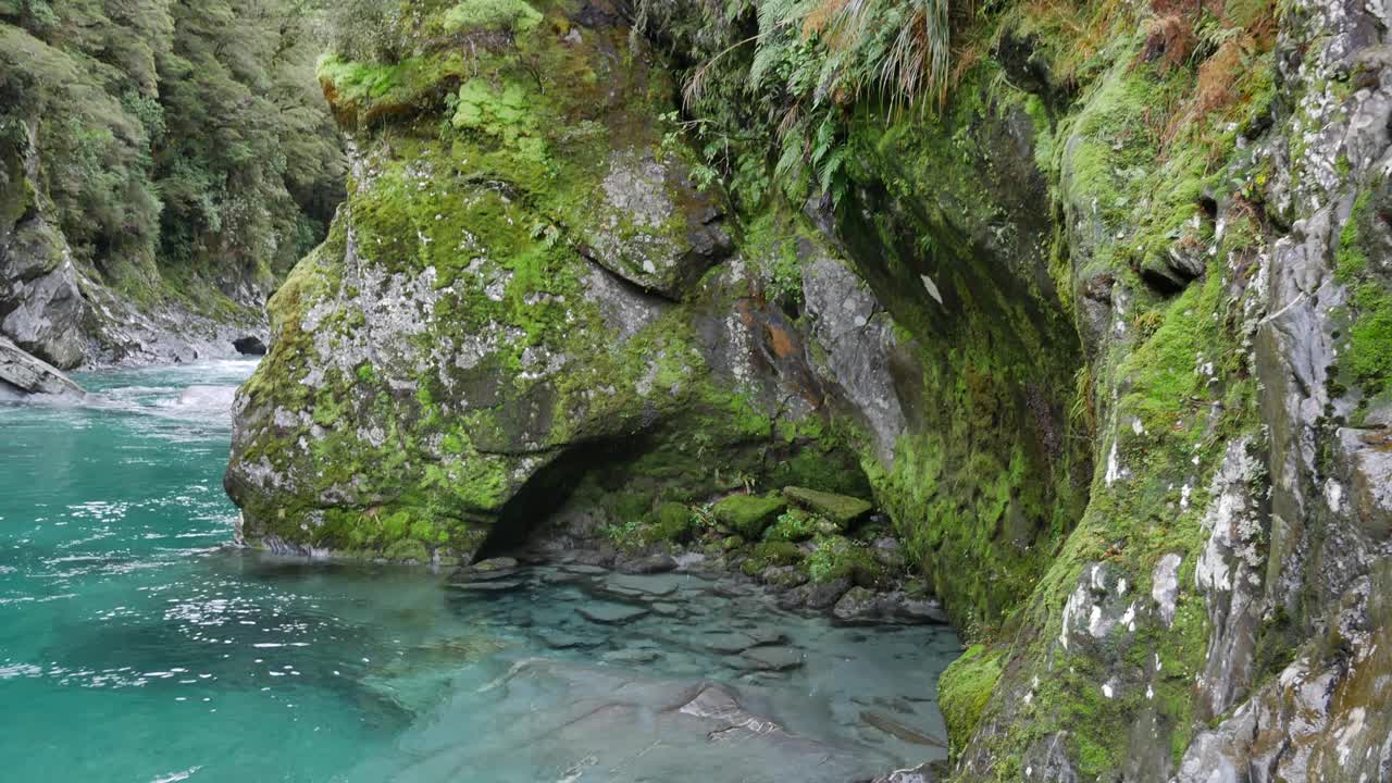 Panoramica verso il basso da una roccia calcarea scolpita e muschiosa alla limpida acqua del fiume sottostante