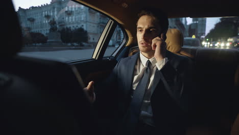 Serious-businessman-talking-mobile-phone-in-car.-Man-working-in-dark-automobile