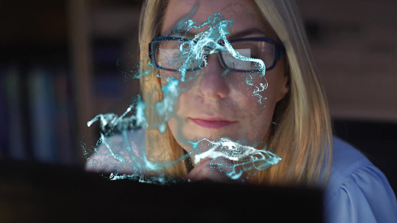 Woman with glasses focused on laptop, abstract blue animation overlay
