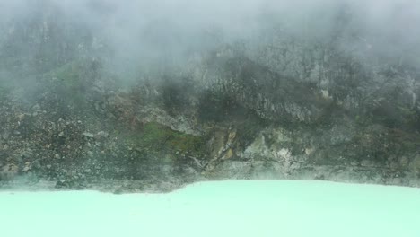 rocky mountain landscape at crater rim of kawah putih with neon water shoreline