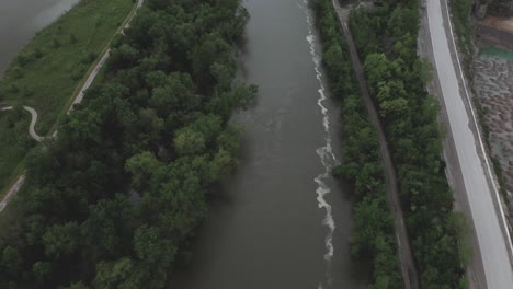 drone flies over a midwestern usa river, camera pans up to reveal a highway in the distance