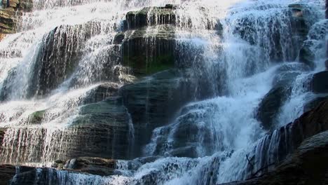 a wide waterfall flows over rock ledges in ithaca falls new york 4