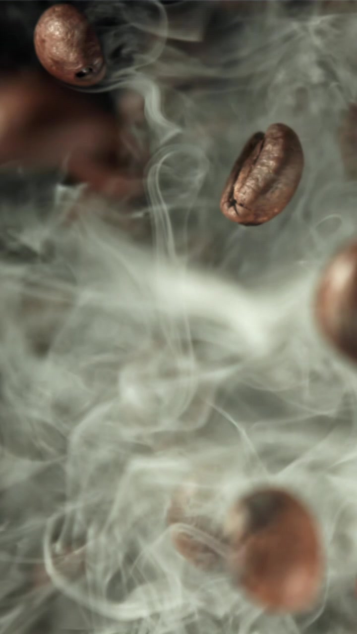 Sakte film av ristede kaffebønner som faller gjennom røyk