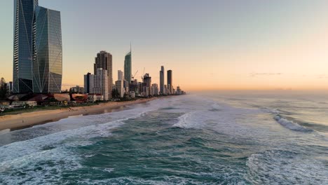 aerial view of gold coast at sunrise, showcasing skyscrapers and ocean waves under soft morning light