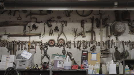 assorted tools and parts organized on a workshop wall above a bench with supplies