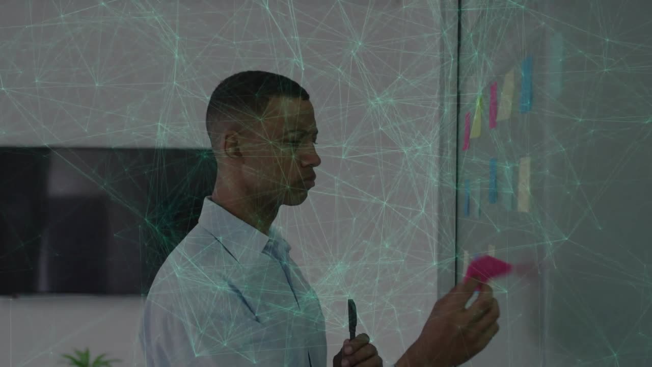 Man peeling pink notes and placing on glass with marker, planning business under turquoise overlay