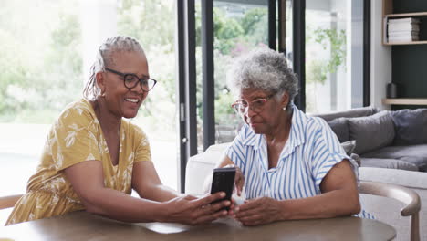 Felices-Amigas-Afroamericanas-Mayores-Usando-Un-Teléfono-Inteligente-Y-Hablando-En-Casa,-En-Cámara-Lenta