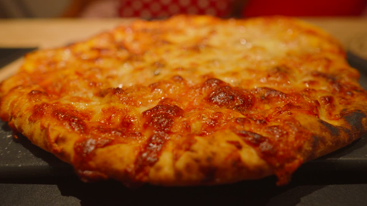 Overview of Rustic Italian Style Cheese and Tomato Margherita Pizza on Wooden Table Setting Ready to Cut into Slices. Close Up Food Footage.