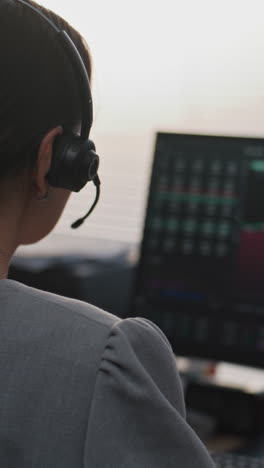 mujer trabajando desde casa, mirando la pantalla de la computadora con gráficos de acciones