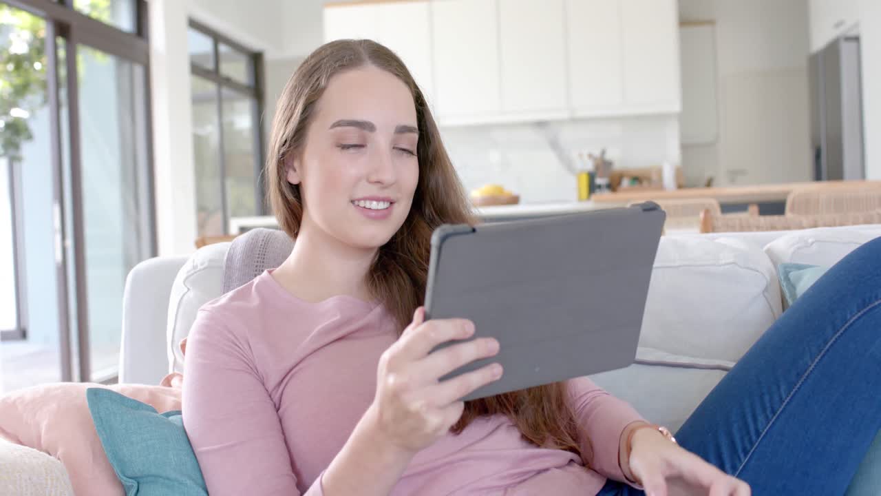 mujer caucásica feliz sosteniendo una tarjeta de crédito y usando una tableta en cámara lenta