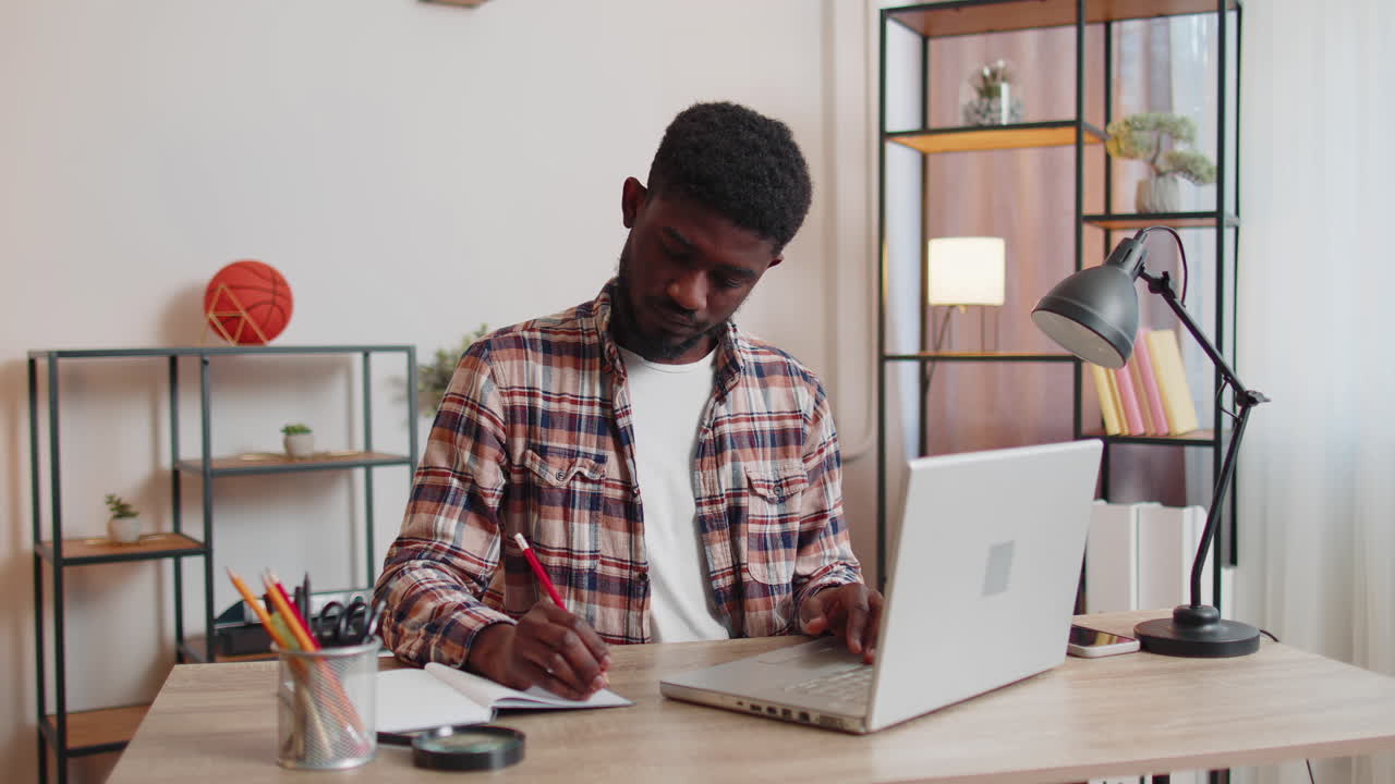 Young man guy using laptop computer sitting at table working, online shopping from home office