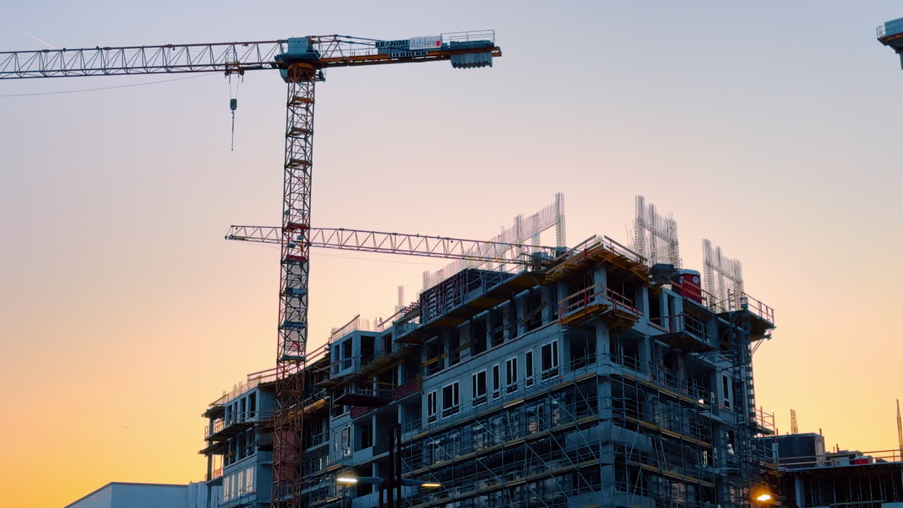 Bratislava, Slovakia - June 5, 2025: New construction project at sunset. A construction site stands against a colorful sunset with cranes and building structures visible in the background