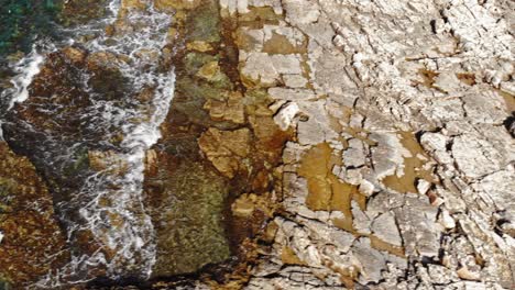 Sea-Waves-Crashing-On-The-Rocky-Shore-At-Paralia-Emplisi-Beach-In-Greece---aerial-drone-shot