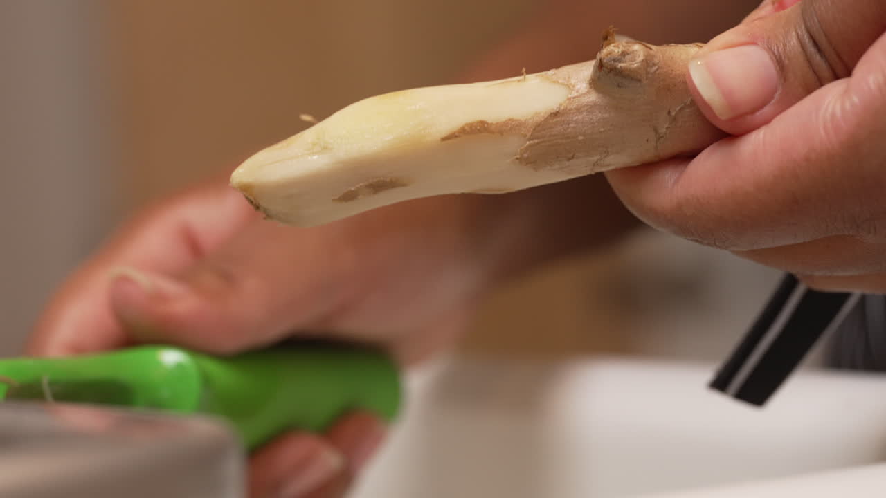 수제 레시피를 위해 부엌 싱크대에서 큰 생강 뿌리 껍질 벗기기 - 슬로우 모션