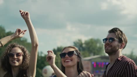 Junge-Kaukasische-Freunde-Tanzen-Auf-Einem-Musikfestival-Mit-Erhobenen-Händen.